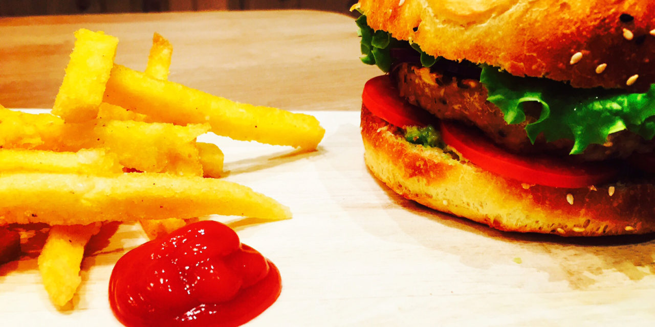 Vegan burger with cereals and lentils steak, spiced avocado sauce and fried polenta chips