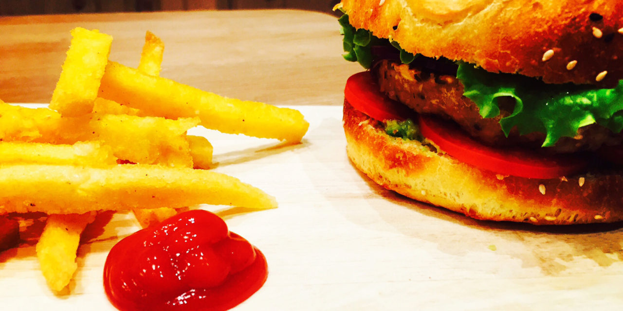 Vegan burger with cereals and lentils steak, spiced avocado sauce and fried polenta chips